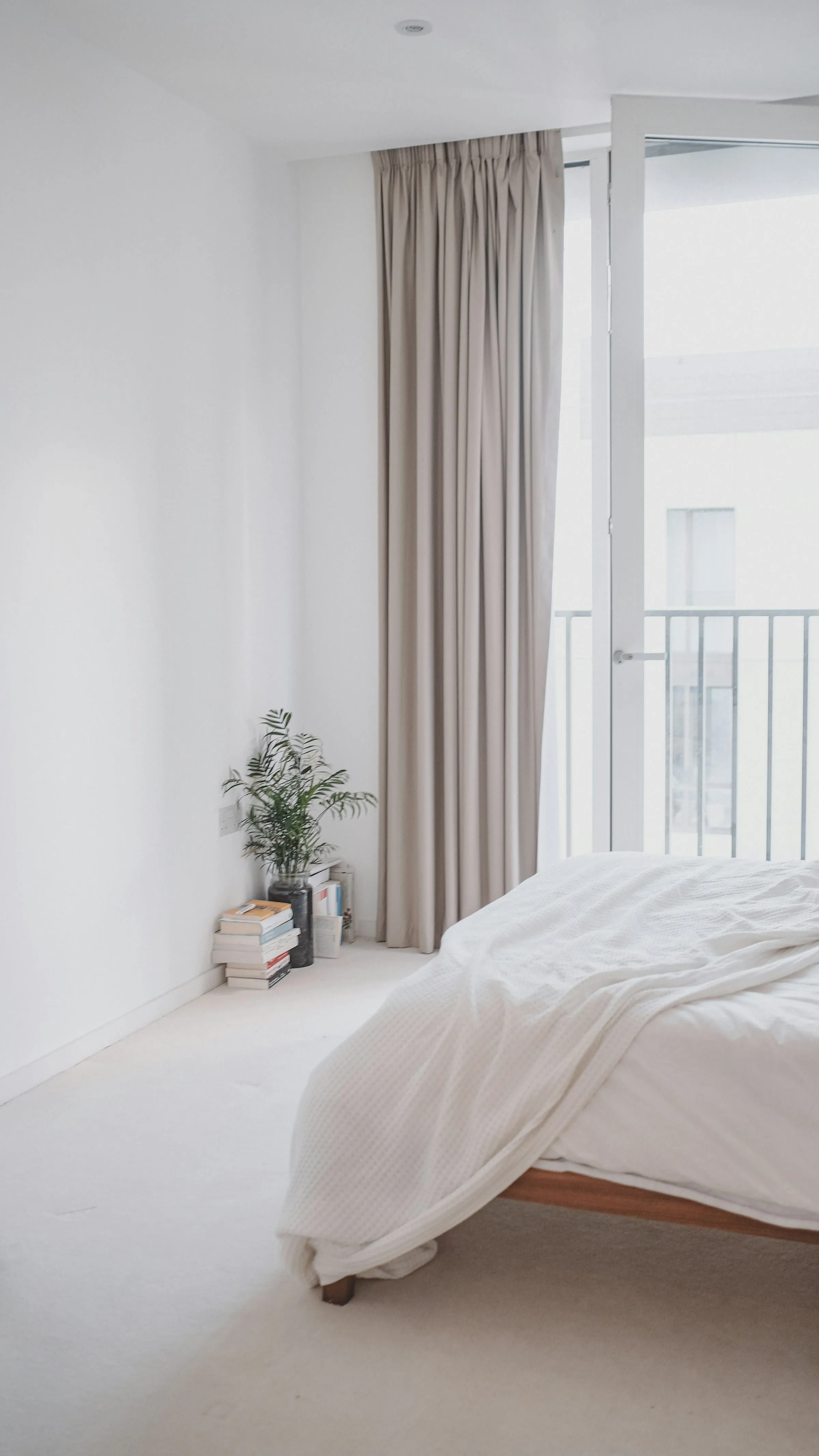 A bright bedroom with daylight coming through a balcony window